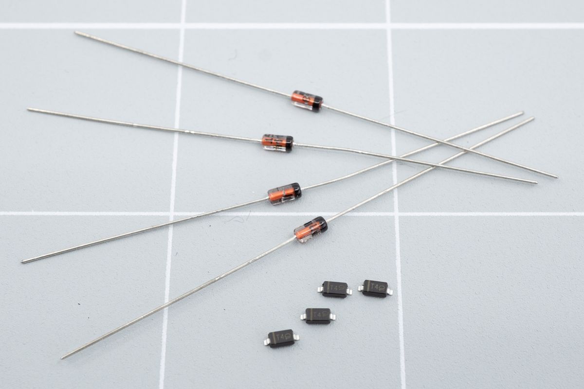 The glass beads on rods are called 'through hole' diodes, while the little black boxes are SMD diodes