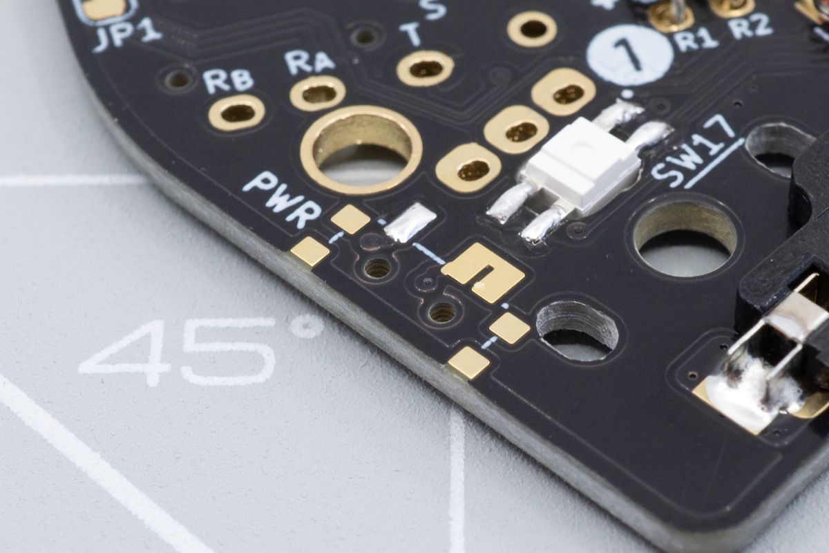 The power switch footprint, with one pad already soldered