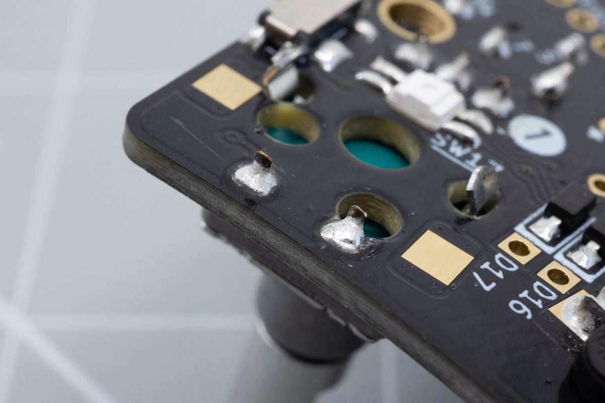 A soldered encoder, looking at the bottom side of the keyboard. Some pads may overlap with switch holes, but you'll still be able to form a good joint