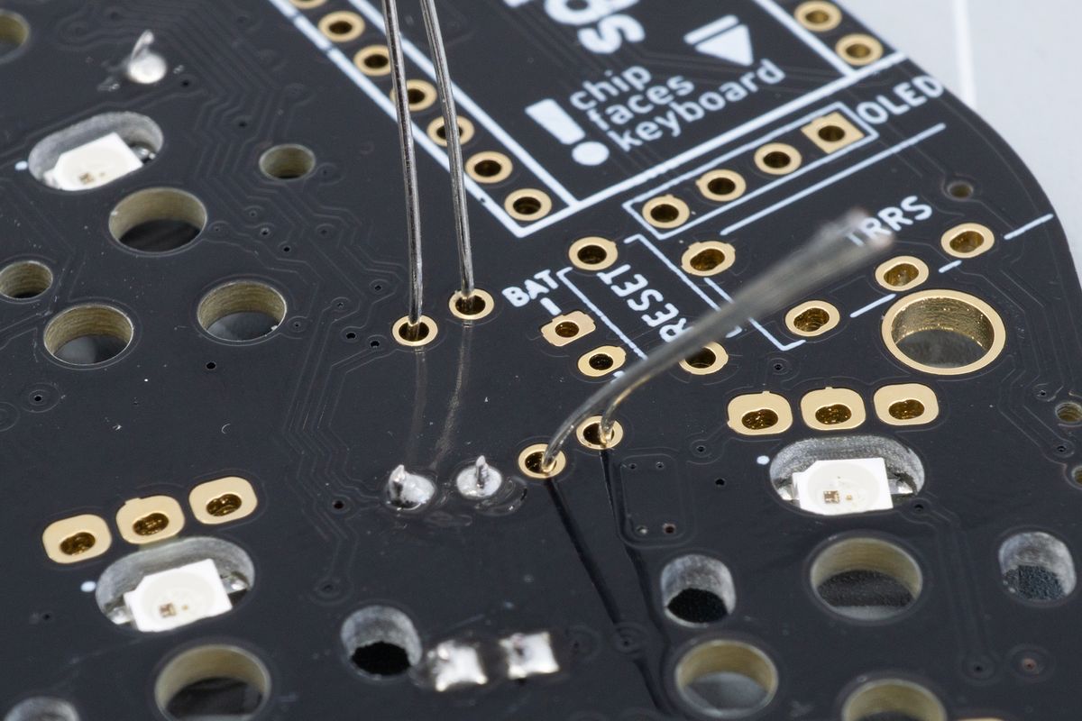 The leads sticking out the other side of the PCB. Note that there's no white outline on this side